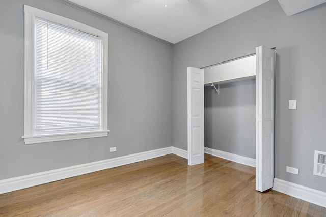 unfurnished bedroom with a closet, baseboards, visible vents, and hardwood / wood-style floors