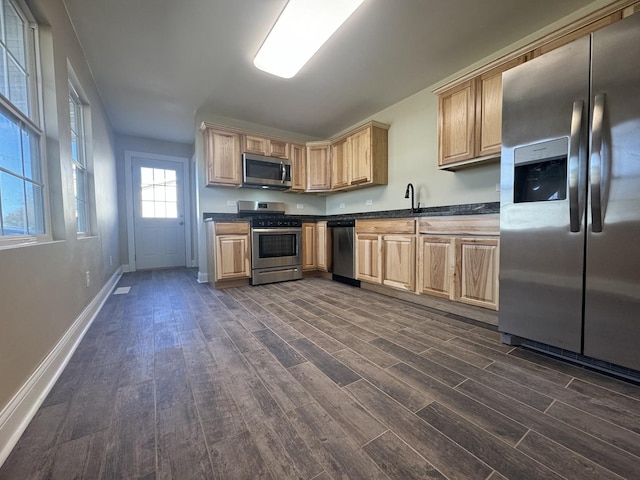 kitchen featuring light brown cabinets, dark wood-type flooring, baseboards, appliances with stainless steel finishes, and dark countertops