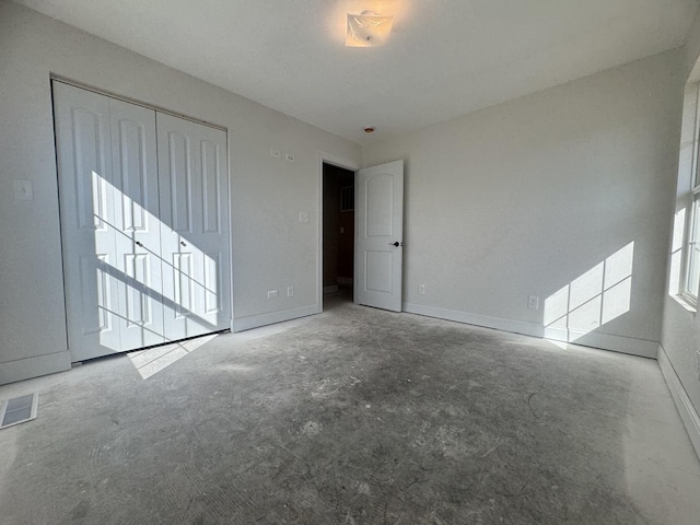 unfurnished room featuring concrete flooring, visible vents, and baseboards