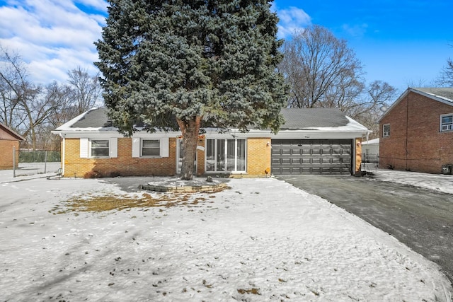 view of front of home featuring aphalt driveway, an attached garage, and brick siding