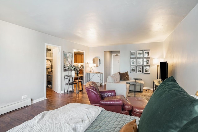 living area with a baseboard heating unit, dark wood-type flooring, and baseboards