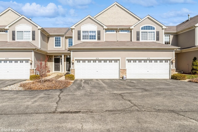 view of property featuring stone siding and driveway