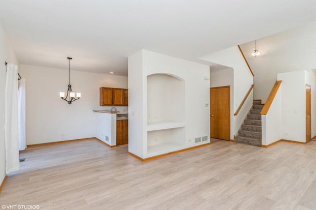 unfurnished living room featuring stairway, baseboards, visible vents, a notable chandelier, and light wood-type flooring