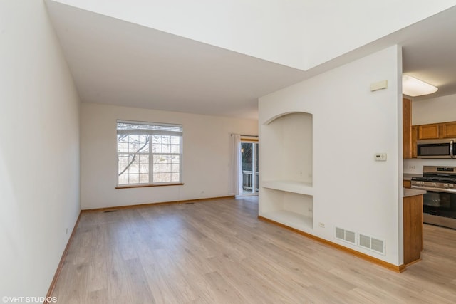 unfurnished living room with visible vents, light wood-type flooring, and baseboards