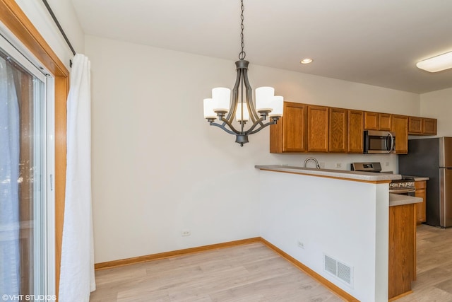 kitchen featuring visible vents, brown cabinets, light wood-style floors, appliances with stainless steel finishes, and a peninsula