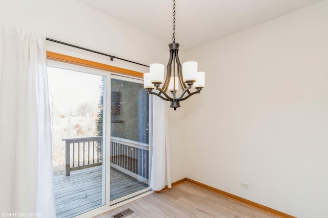 interior space with light wood-type flooring, visible vents, baseboards, and a chandelier