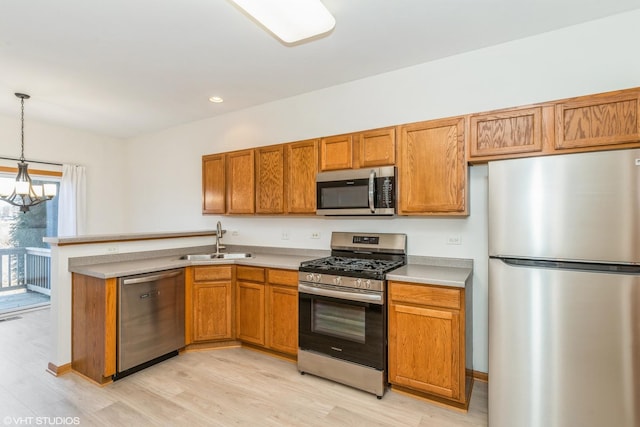 kitchen featuring decorative light fixtures, brown cabinets, stainless steel appliances, and a sink