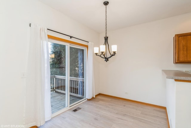 unfurnished dining area featuring an inviting chandelier, baseboards, visible vents, and light wood-type flooring