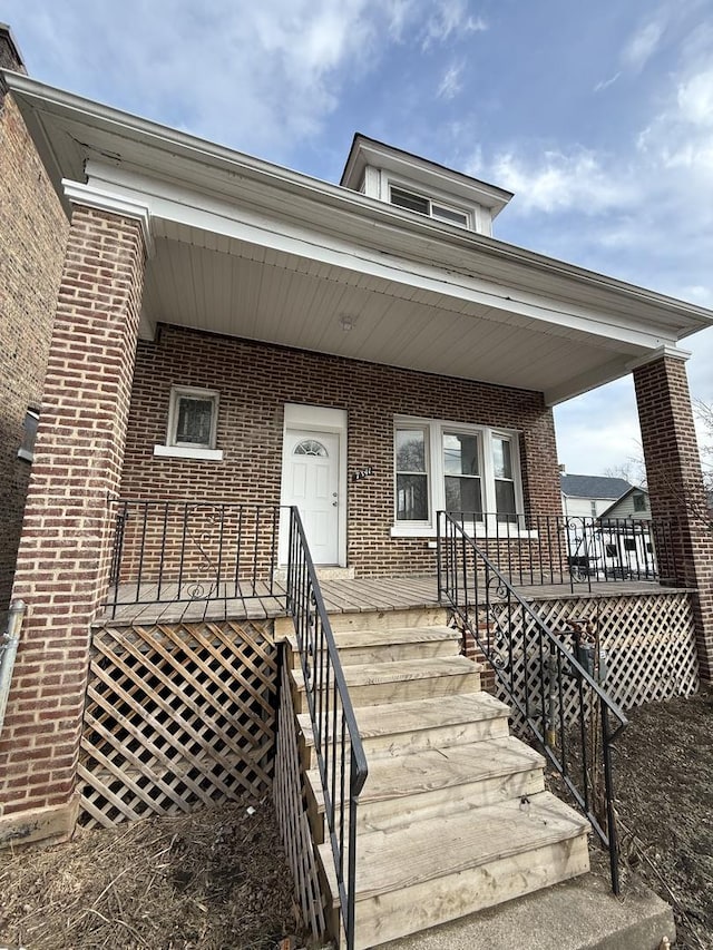 doorway to property featuring brick siding and a porch