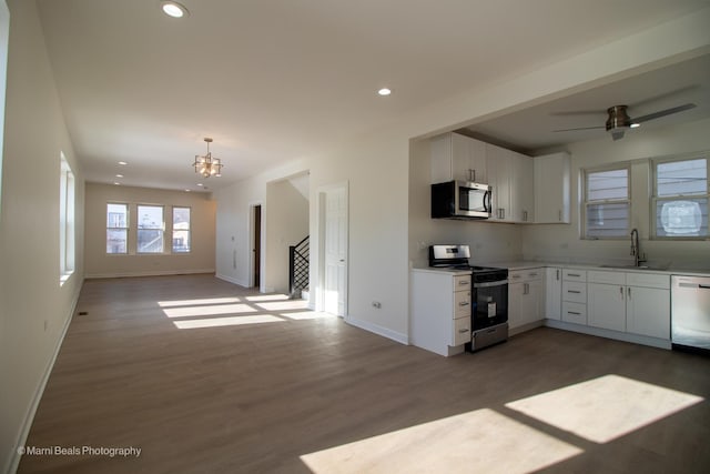 kitchen featuring stainless steel appliances, recessed lighting, light countertops, open floor plan, and wood finished floors