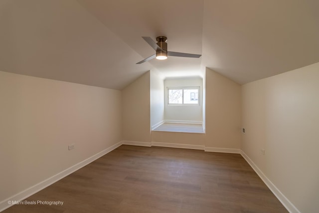 bonus room with dark wood-style floors, lofted ceiling, a ceiling fan, and baseboards