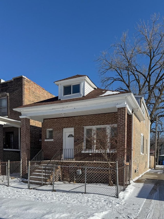 bungalow featuring brick siding, a fenced front yard, and a porch