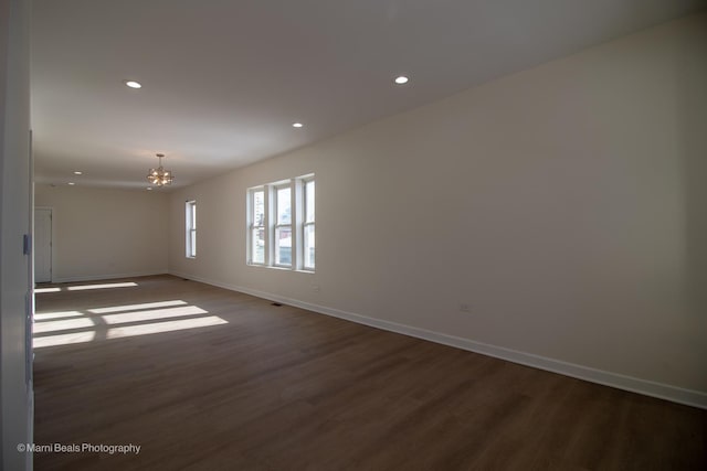 empty room featuring recessed lighting, dark wood finished floors, an inviting chandelier, and baseboards