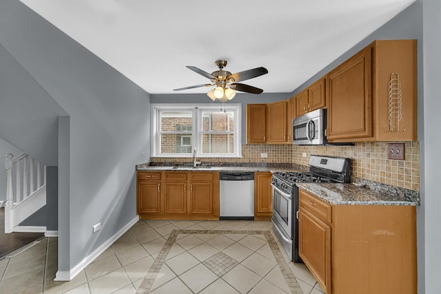 kitchen featuring light tile patterned floors, appliances with stainless steel finishes, a sink, and tasteful backsplash