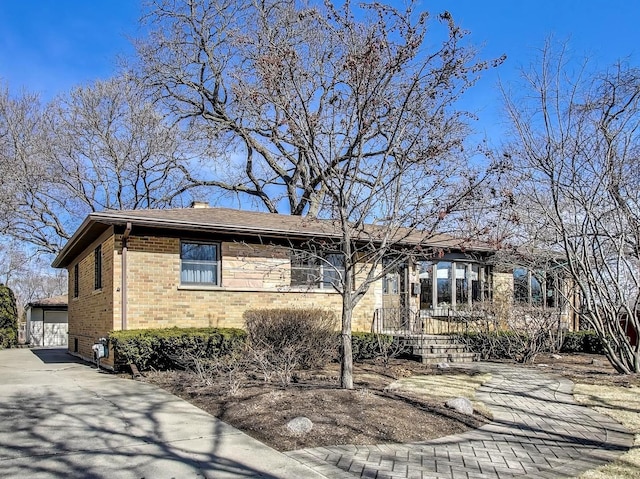 ranch-style home with an outdoor structure, a garage, brick siding, and a chimney