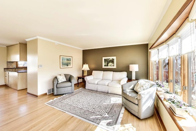 living area featuring visible vents, crown molding, and light wood finished floors