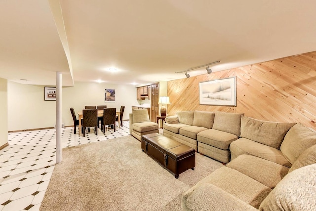 living room with wooden walls, light colored carpet, rail lighting, and baseboards