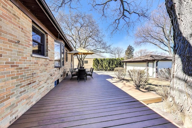 wooden terrace with an outbuilding and outdoor dining space