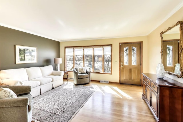 living area featuring light wood finished floors, visible vents, crown molding, and baseboards