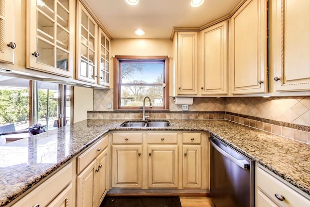 kitchen featuring a sink, light stone counters, plenty of natural light, and dishwasher