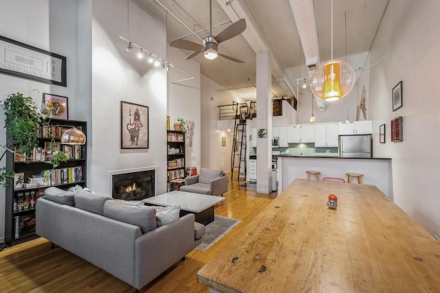 living room with hardwood / wood-style flooring, ceiling fan, and a towering ceiling