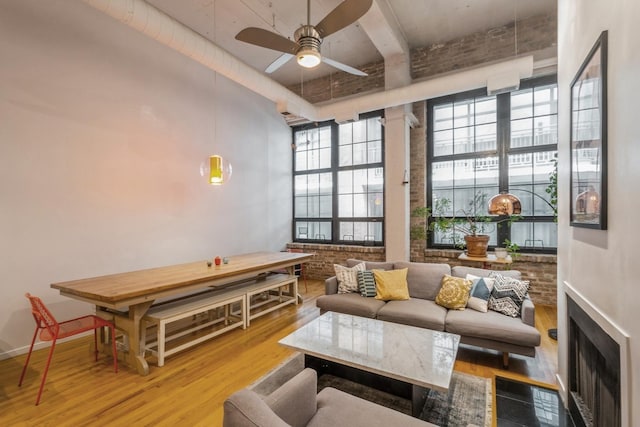 living room featuring light hardwood / wood-style flooring, ceiling fan, and brick wall