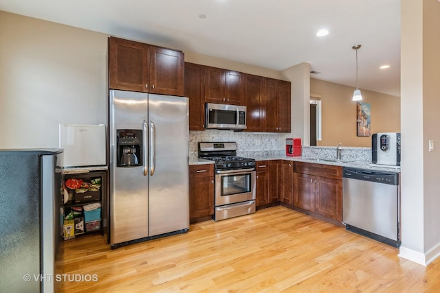 kitchen featuring stainless steel appliances, light wood-style floors, light stone counters, and tasteful backsplash