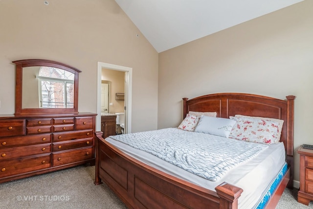 bedroom featuring lofted ceiling, light colored carpet, and ensuite bath