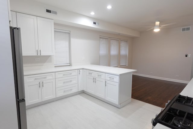 kitchen featuring ceiling fan, stainless steel fridge, white cabinetry, and kitchen peninsula