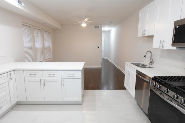 kitchen with stainless steel appliances, ceiling fan, sink, white cabinetry, and kitchen peninsula