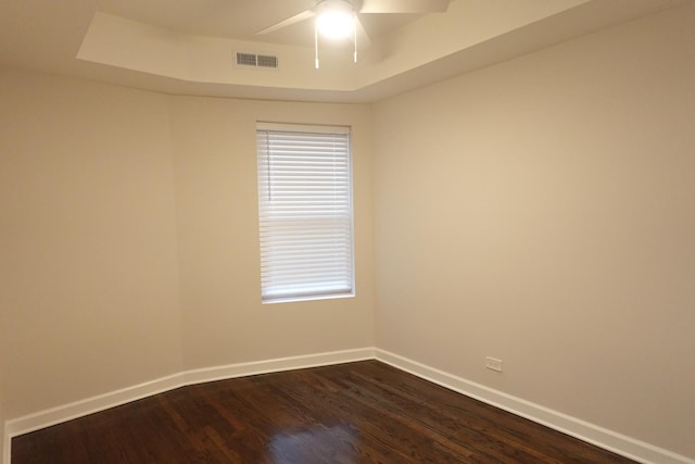 empty room featuring ceiling fan, dark hardwood / wood-style flooring, and a raised ceiling