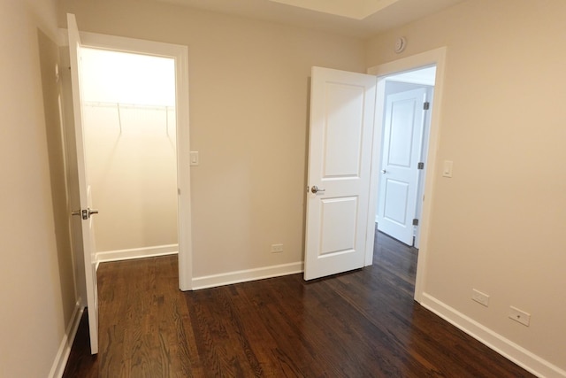 unfurnished bedroom with a walk in closet and dark hardwood / wood-style floors