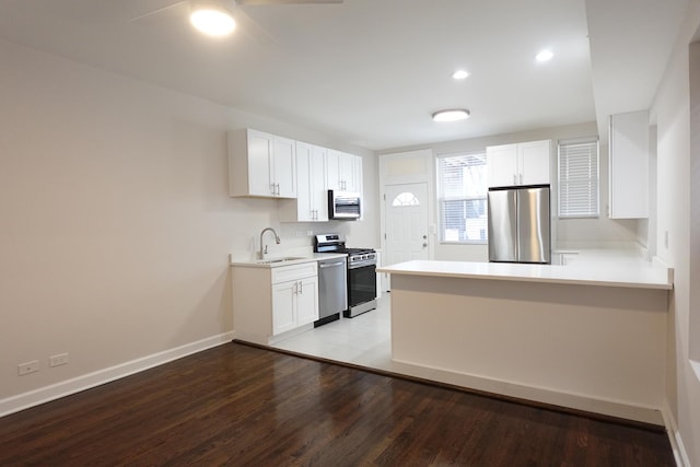 kitchen with light hardwood / wood-style flooring, sink, stainless steel appliances, kitchen peninsula, and white cabinets