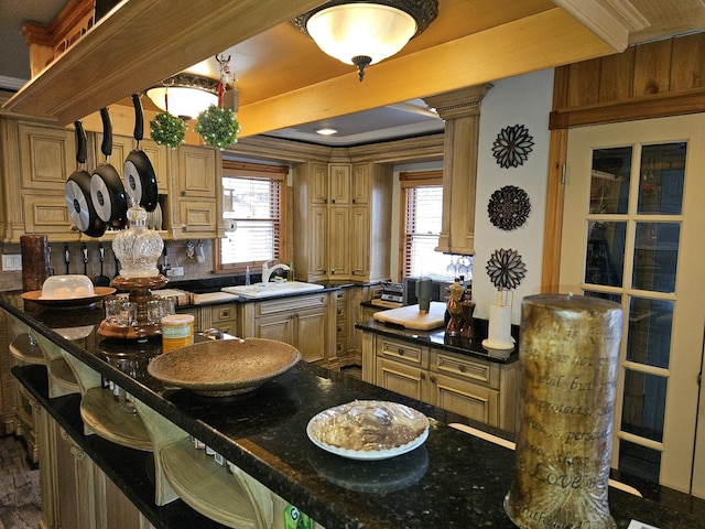 kitchen with a kitchen breakfast bar, sink, decorative columns, and light brown cabinetry