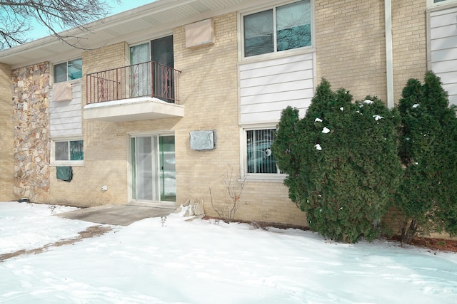 snow covered house with brick siding and a balcony