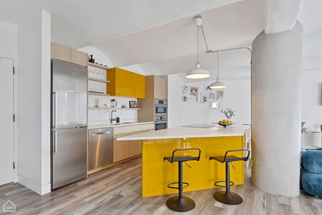 kitchen featuring hanging light fixtures, stainless steel appliances, a kitchen island, and a breakfast bar area