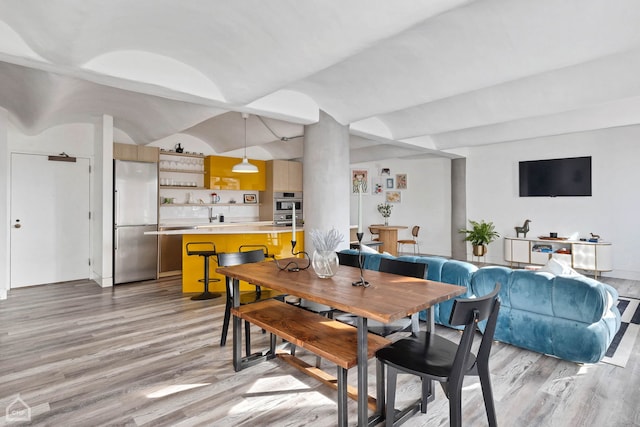 dining room featuring light hardwood / wood-style flooring, indoor bar, and lofted ceiling