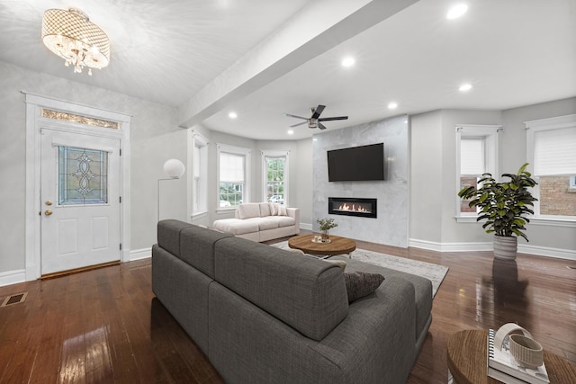 living room featuring ceiling fan with notable chandelier, dark hardwood / wood-style floors, and a fireplace