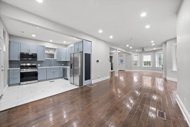 kitchen with appliances with stainless steel finishes, sink, light hardwood / wood-style flooring, ceiling fan, and decorative backsplash