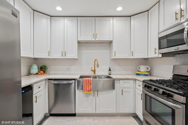 kitchen featuring appliances with stainless steel finishes, white cabinets, light countertops, and a sink