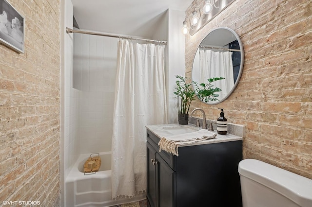 full bath featuring shower / bath combo, toilet, vanity, and brick wall