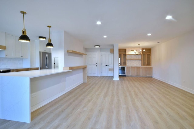 kitchen with open shelves, tasteful backsplash, stainless steel refrigerator, and light countertops