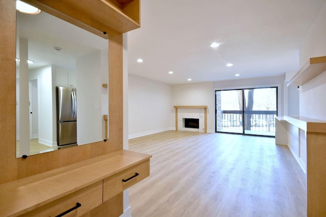 unfurnished living room featuring light wood-style floors, a fireplace, baseboards, and recessed lighting