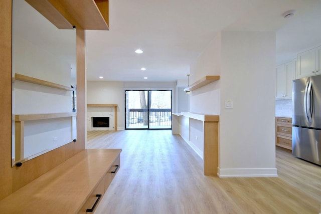 unfurnished living room with light wood finished floors, a premium fireplace, recessed lighting, and baseboards