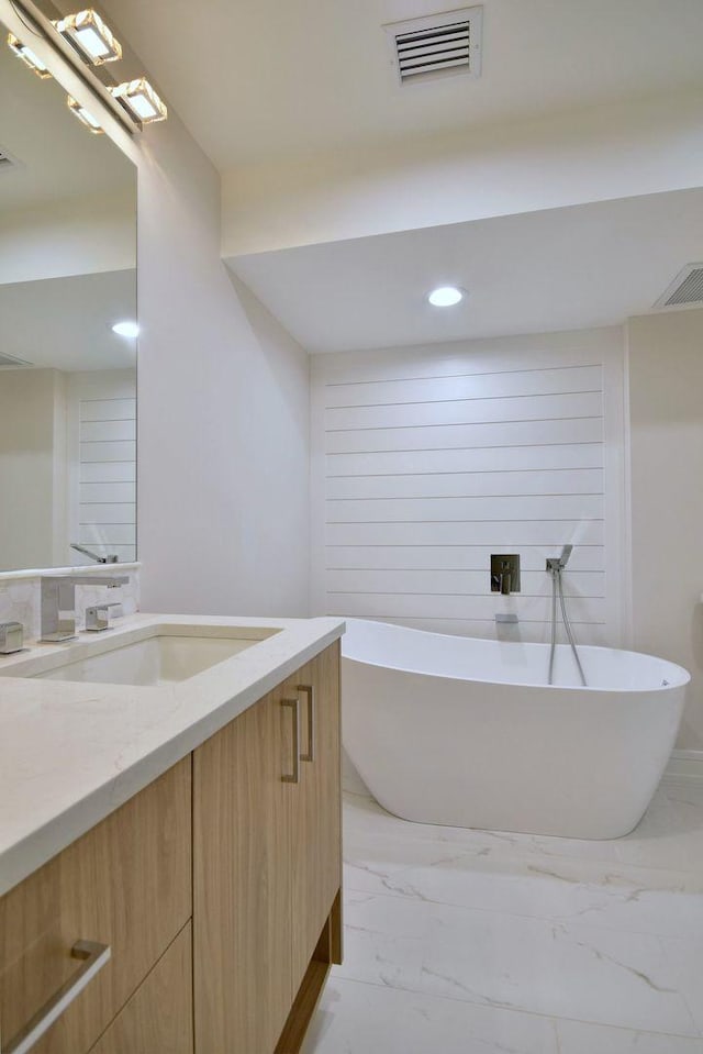 full bath with marble finish floor, visible vents, a freestanding bath, and vanity