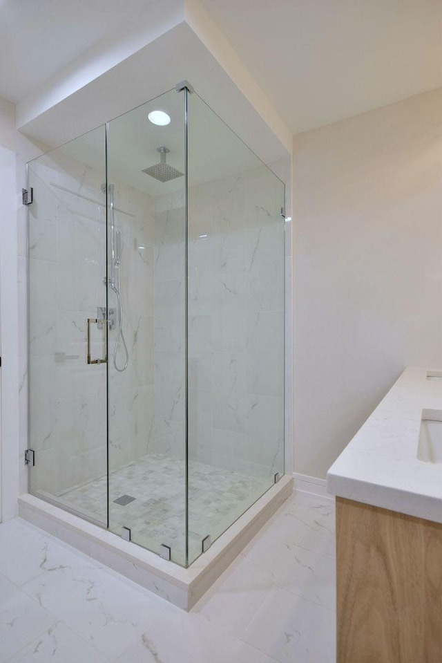 full bath featuring marble finish floor, a marble finish shower, baseboards, and vanity