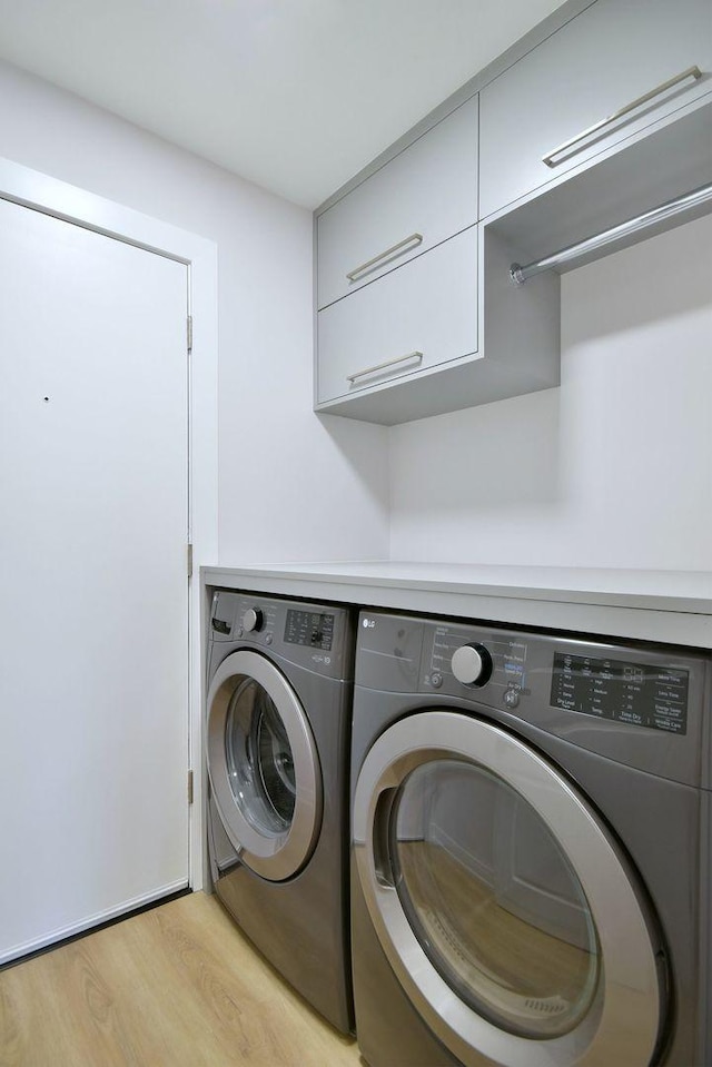 laundry room featuring cabinet space, independent washer and dryer, and light wood-style flooring