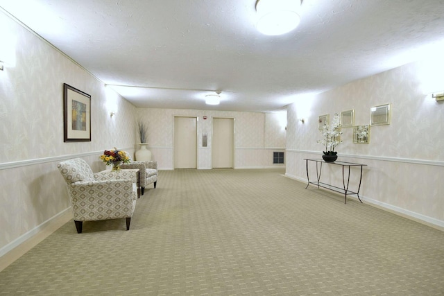 living area with carpet, a wainscoted wall, a textured ceiling, and wallpapered walls