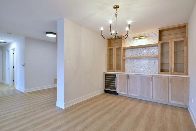 bar with wine cooler, light wood-style flooring, and baseboards