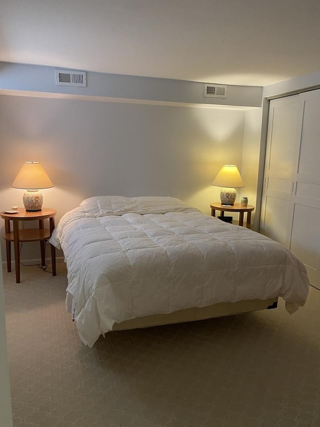 carpeted bedroom featuring a closet and visible vents